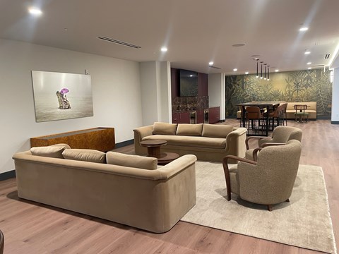 A living room with a couch, chairs, and a painting of a person sitting on a chair.