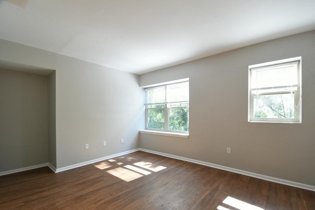 a bedroom with two windows and hardwood floors
