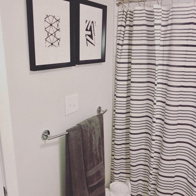 a bathroom with a striped shower curtain and pictures on the wall at Carver and Slowe Apartments, Washington