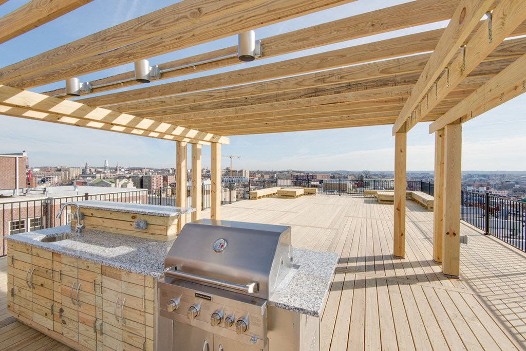 a rooftop deck with a barbecue and a view of the city