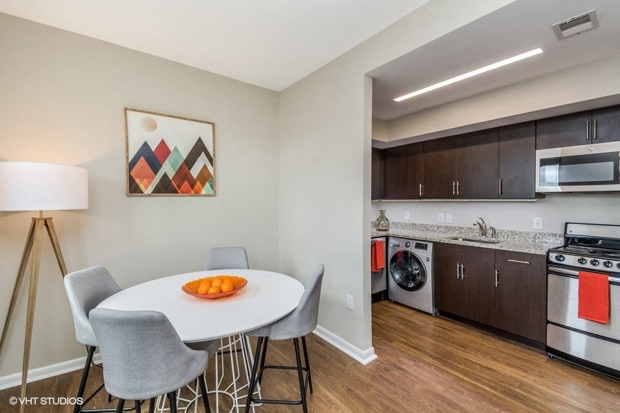 a dining area with a table and chairs and a kitchen with a washer and dryer