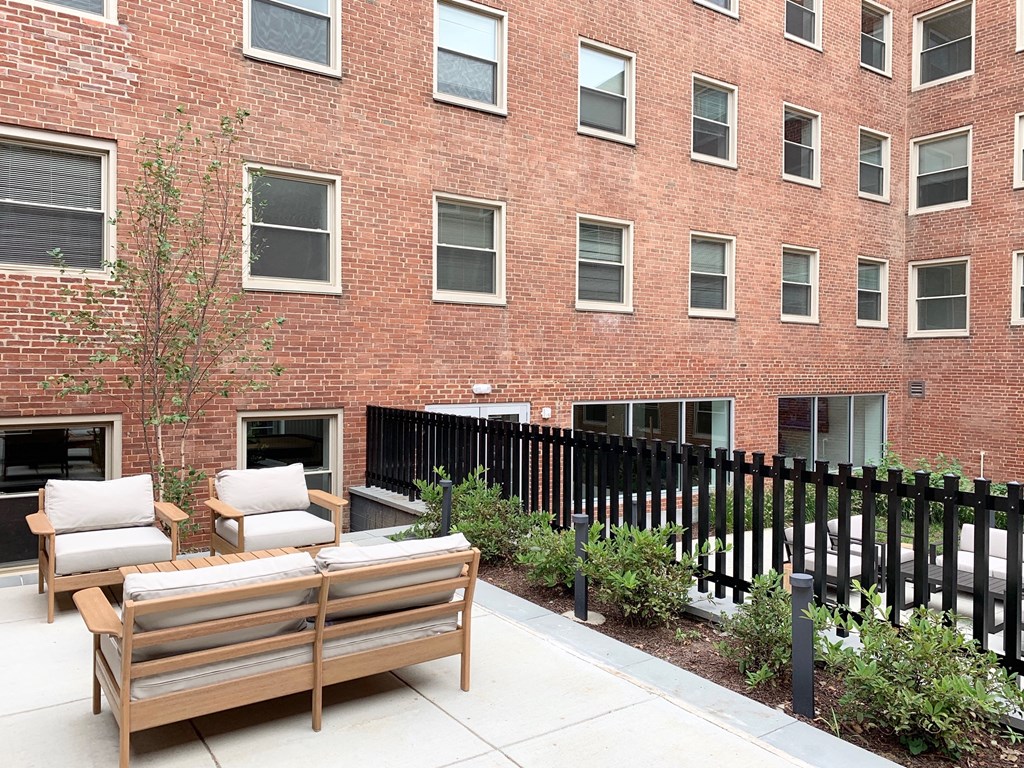 a patio with two chairs and a table in front of a brick building at Carver and Slowe Apartments, Washington, DC, 20001