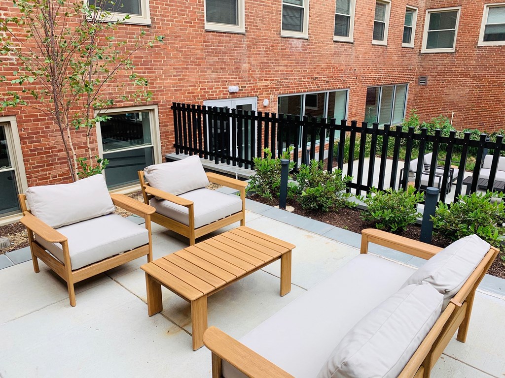a patio with wooden furniture and a brick building in the background at Carver and Slowe Apartments, Washington, DC