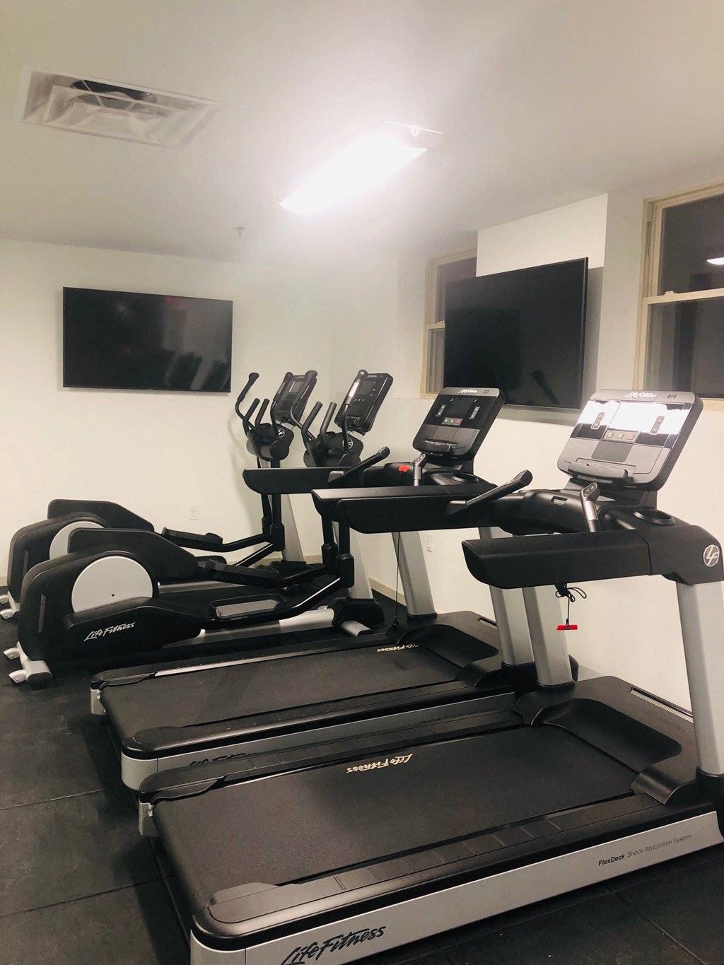 a gym with treadmills and a flat screen tv at Carver and Slowe Apartments, Washington, DC