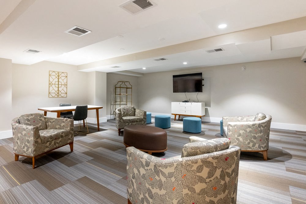 a room with couches and chairs and a table with a television on the wall