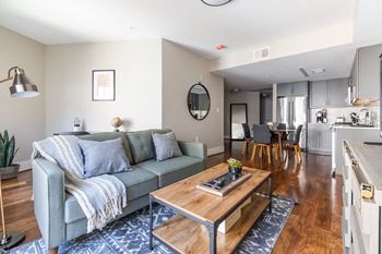 a living area with a couch coffee table and a kitchen in the background
