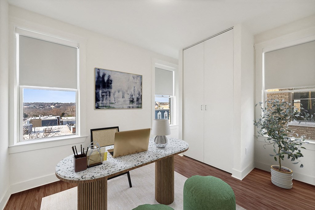 an office with a desk with a laptop and a window