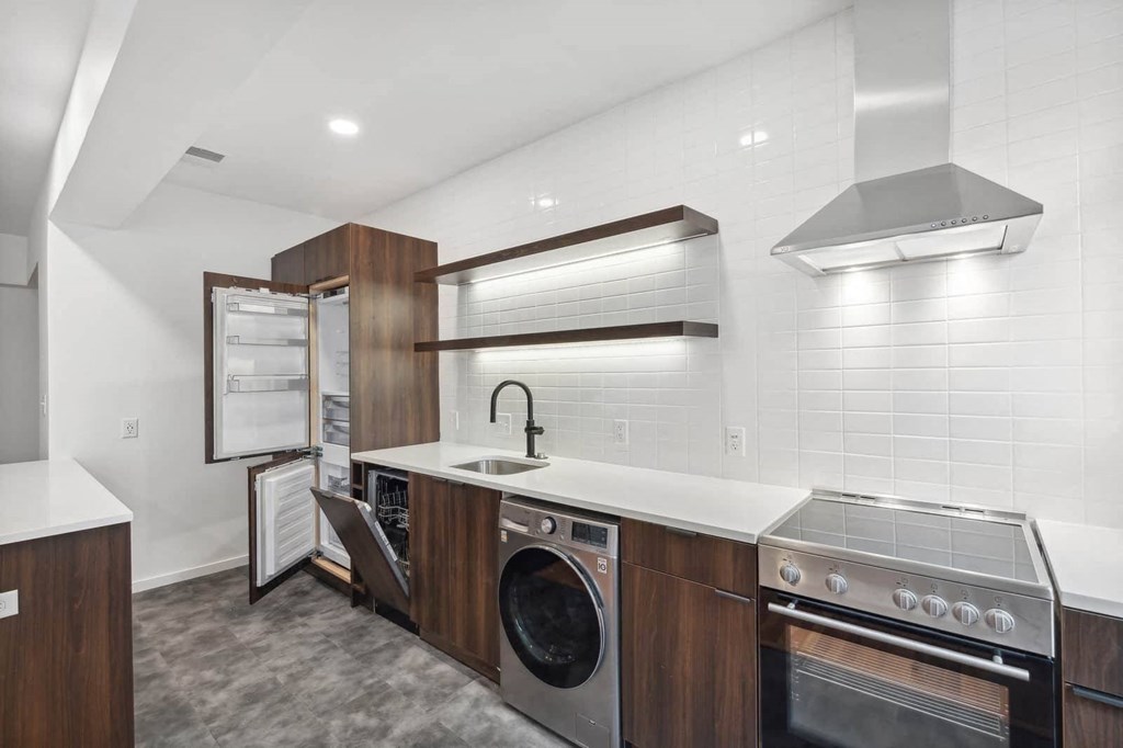 a kitchenette with white countertops and wooden cabinetry