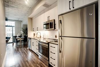 a kitchen with stainless steel appliances and white cabinets at Coda on H Apartments, Washington