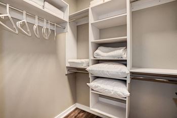 a walk in closet with white shelves and pillows at Coda on H Apartments, Washington, District of Columbia
