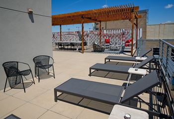 a rooftop patio with tables and chairs and a pergola