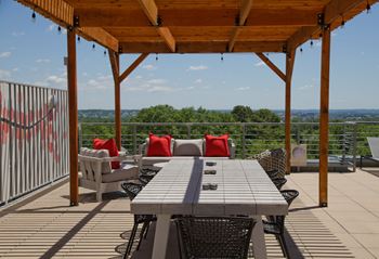 a wooden table with chairs on a wooden deck with a view of the city in the background