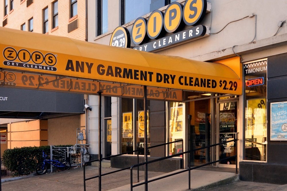 a store front of a building with a yellow sign that reads any garment dry cleaned at The Chesapeake Apartments, Washington 20008