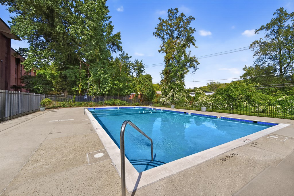 A rectangular pool surrounded by a concrete floor and a metal fence.