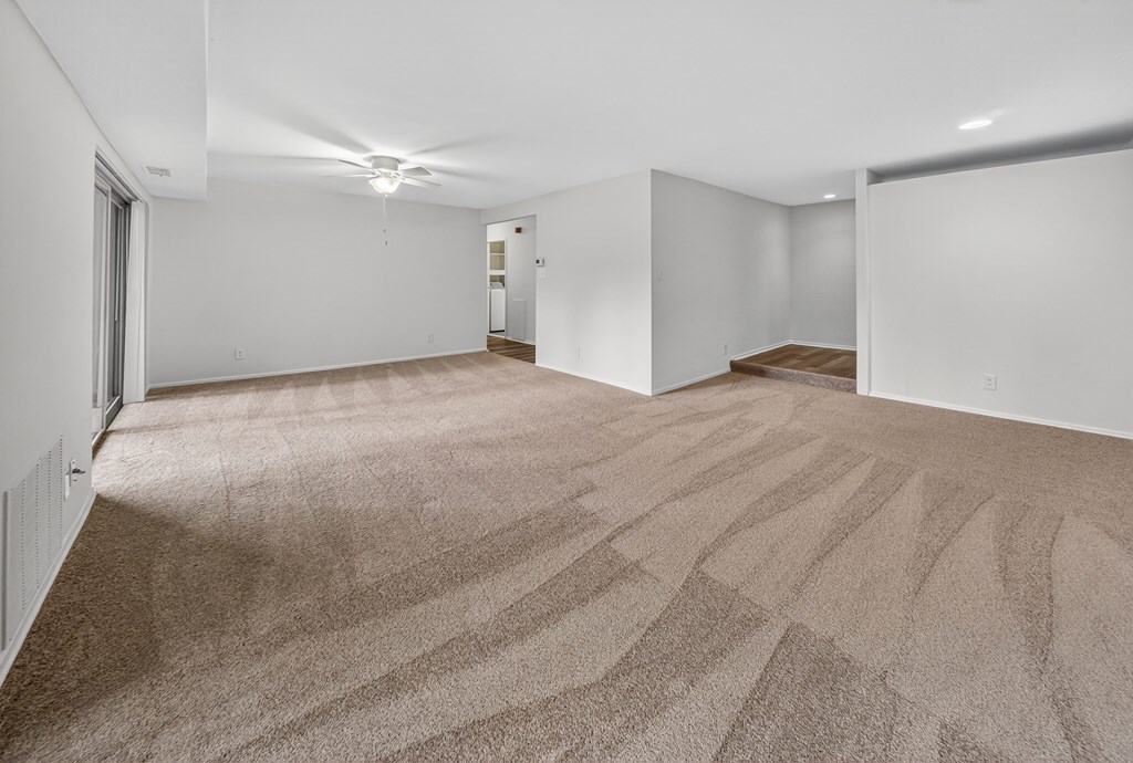 A large, empty room with carpeted flooring and white walls.