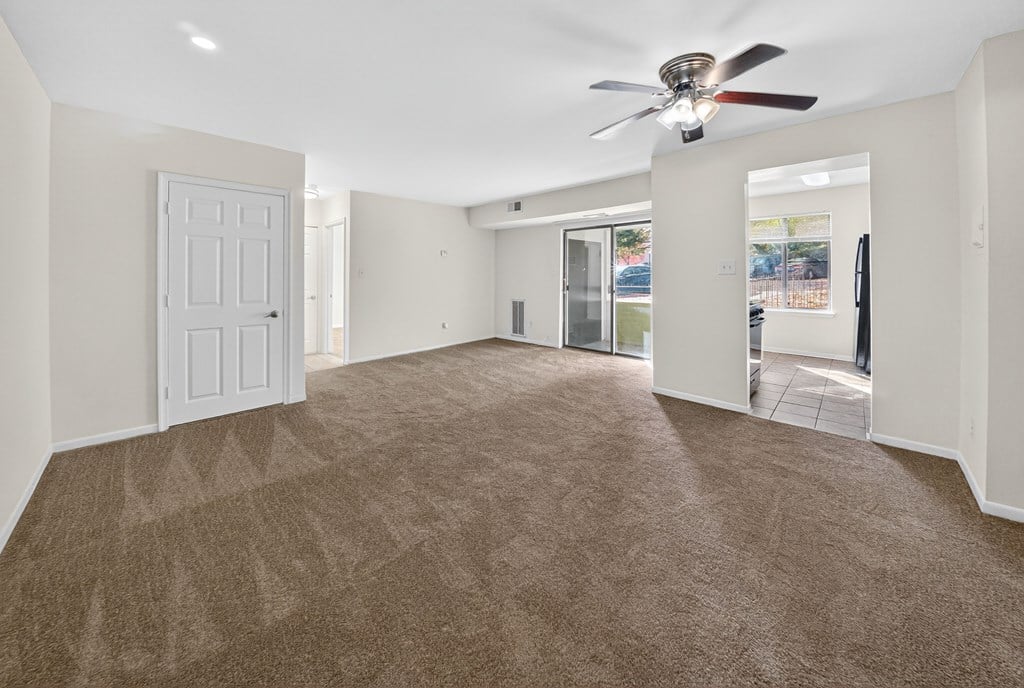 A spacious room with a carpeted floor and a ceiling fan.