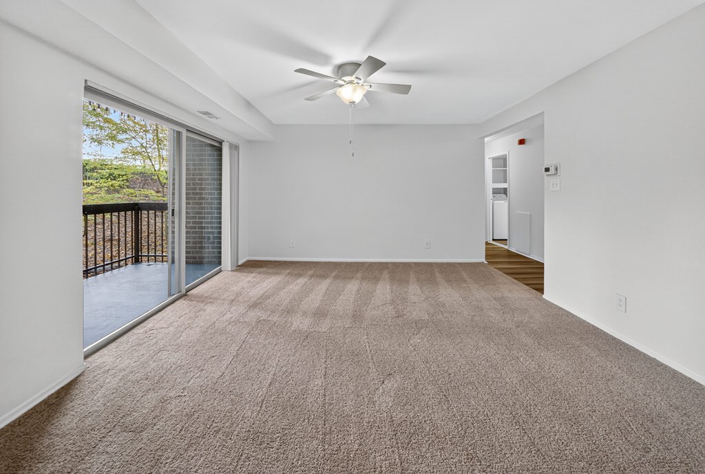 A room with a carpeted floor and a ceiling fan.