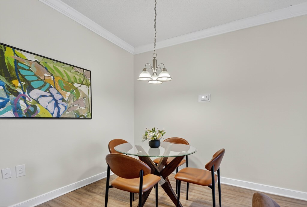 A dining room with a table set for two and a painting on the wall.