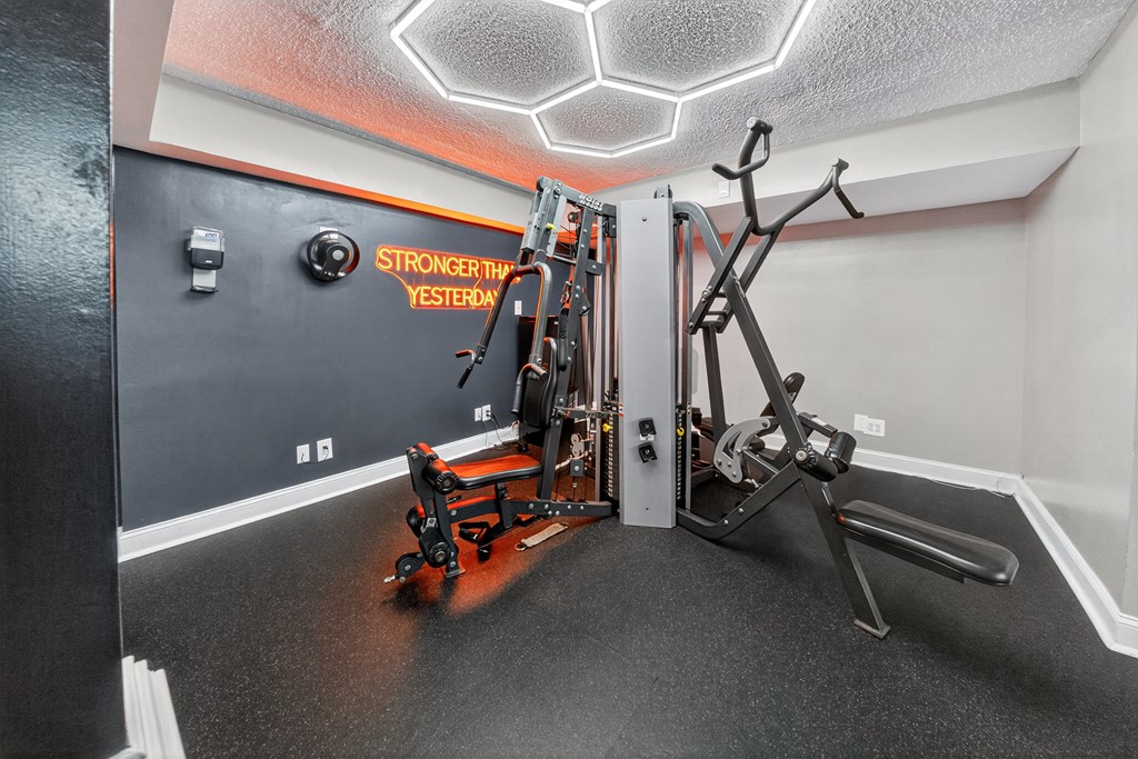 A gym room with a rowing machine and a weight machine.