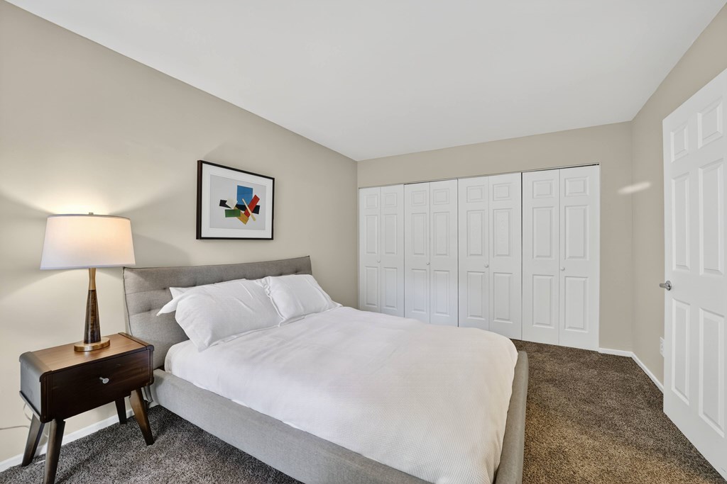 A bedroom with a bed, nightstand, and lamp.