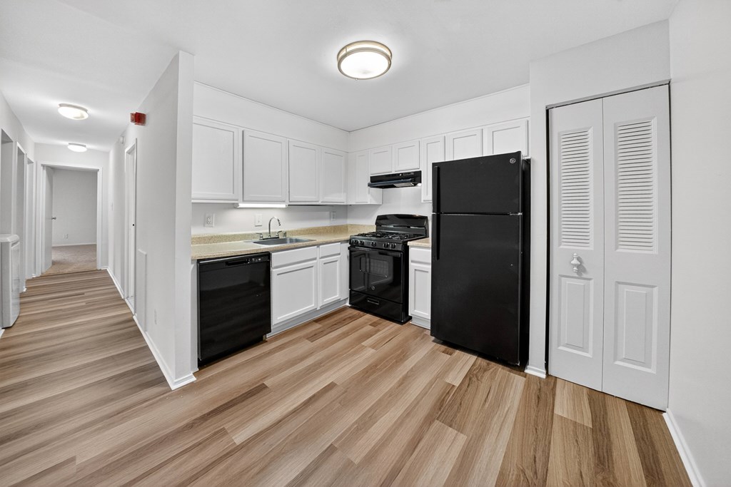 A kitchen with black appliances and white cabinets.