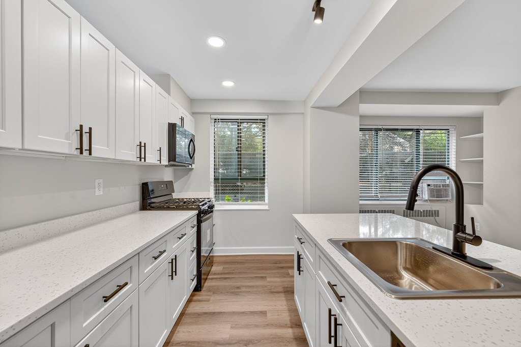 A kitchen with white cabinets and a large sink.