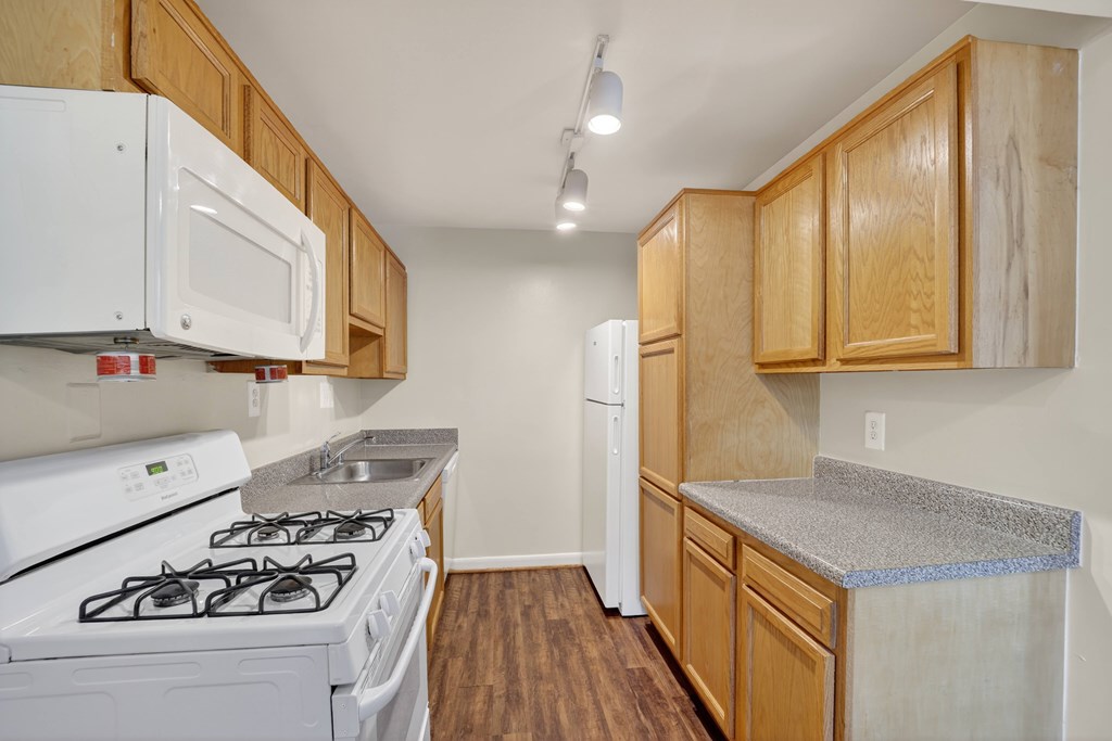 A kitchen with white appliances and wooden cabinets.