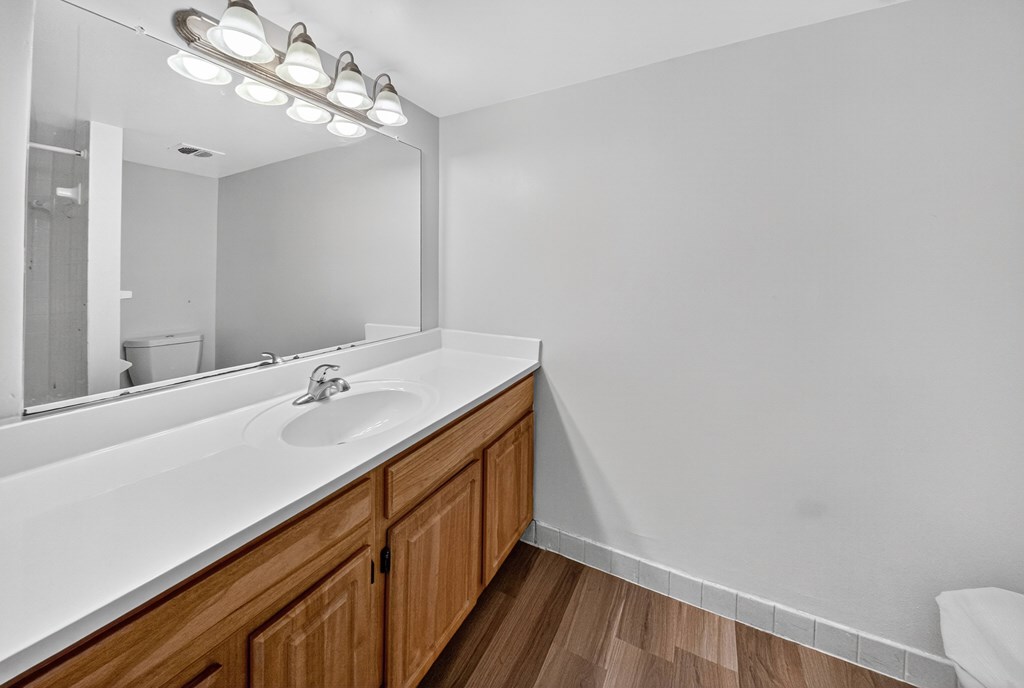 A bathroom with a white countertop and wooden cabinets.