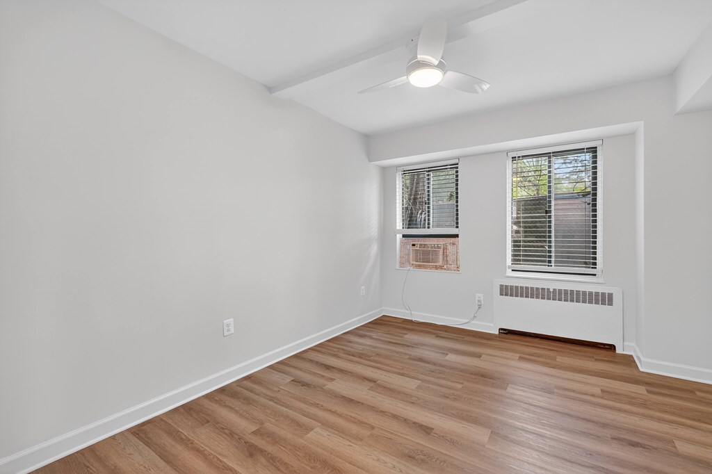 A room with a window and a fan on the ceiling.
