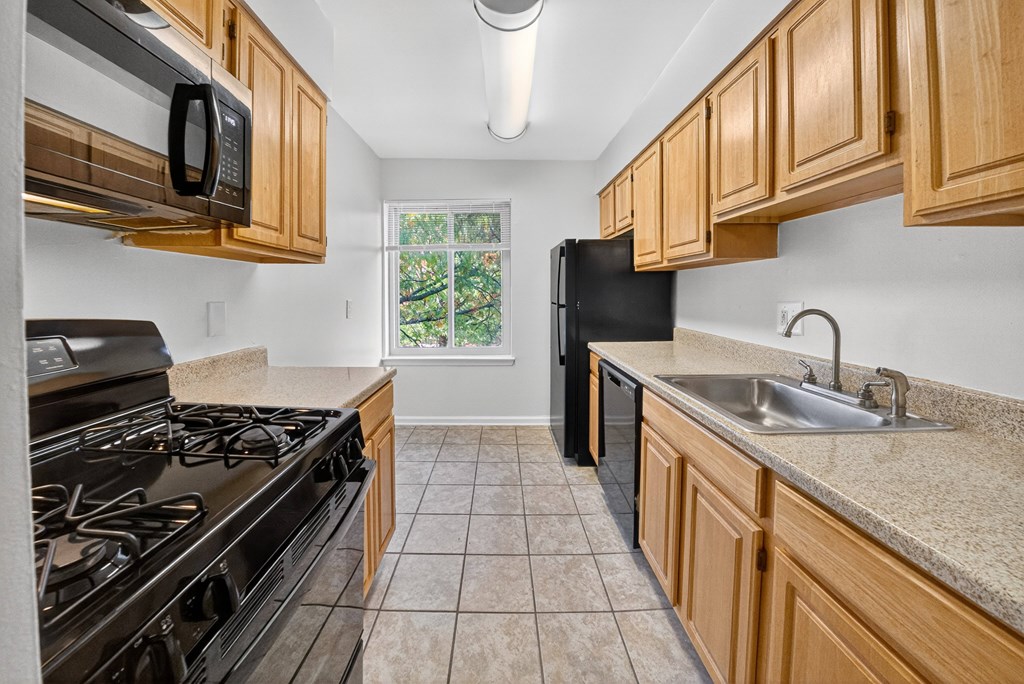 A kitchen with a black stove top oven and black microwave.