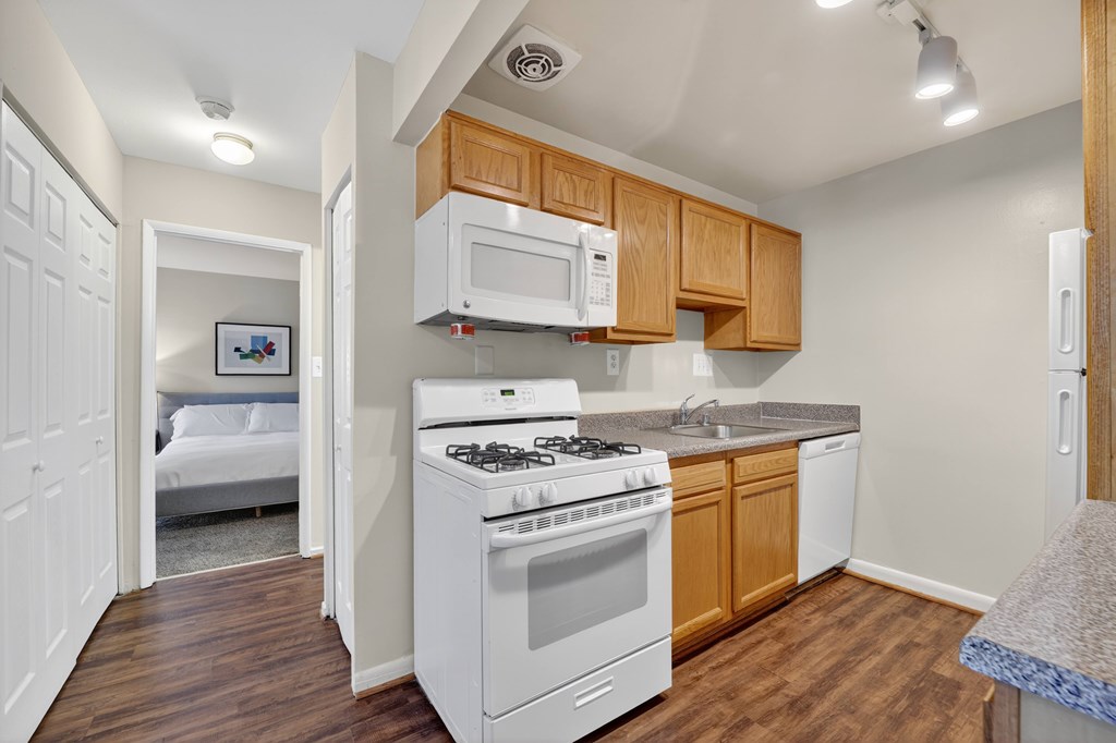 A small kitchen with a white stove and wooden cabinets.