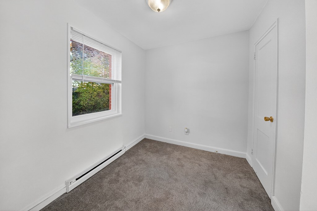 A room with a window and a carpeted floor.