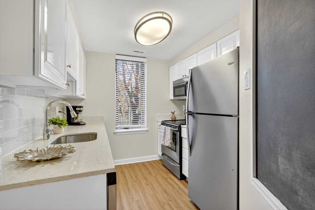 A kitchen with a refrigerator, sink, and window.