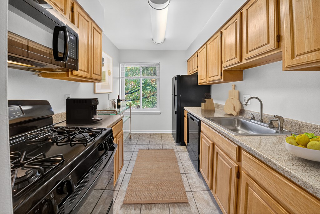 A kitchen with black appliances and wooden cabinets.