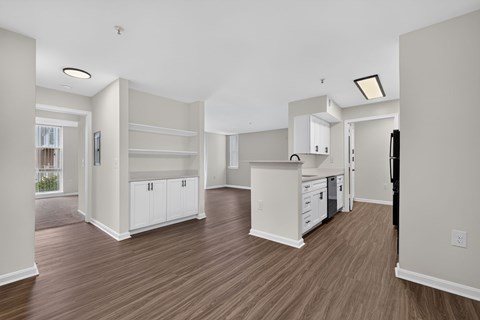 A kitchen with white cabinets and a wooden floor.