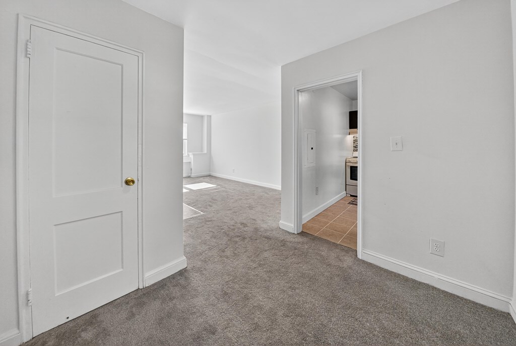 A white door with a gold handle is on the left and an open door with a white frame is on the right.