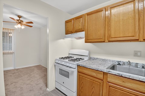 A kitchen with a white stove and wooden cabinets.
