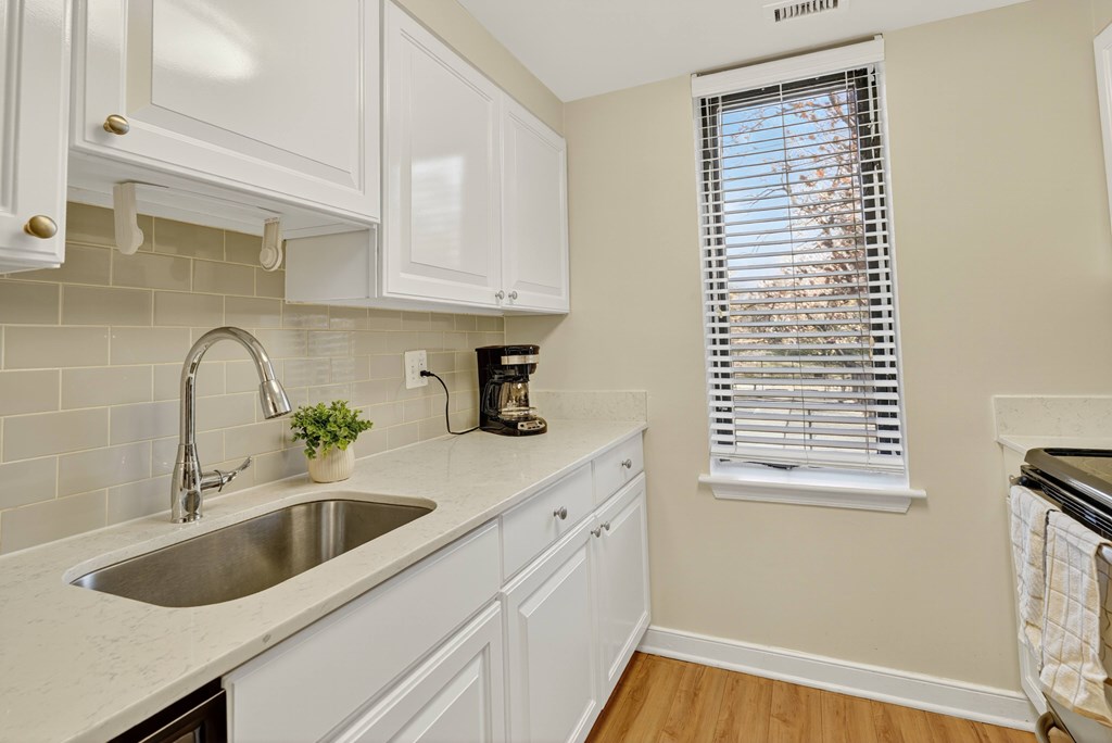 A kitchen with white cabinets and a stainless steel sink.