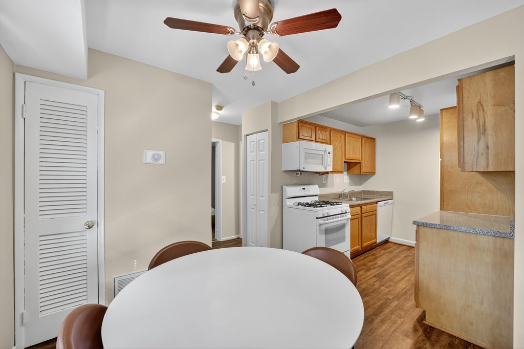 A kitchen with a white ceiling fan and a white table.