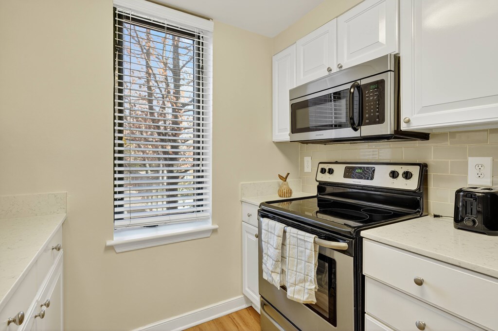 A kitchen with a stove, microwave, and oven.