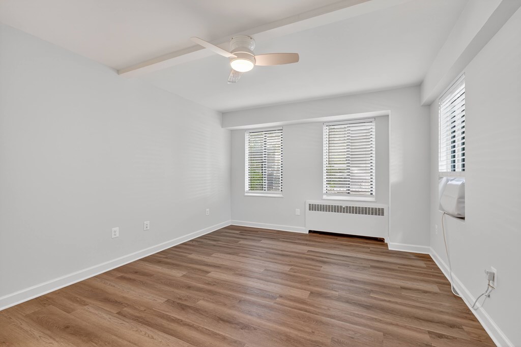 A room with a ceiling fan and wooden flooring.