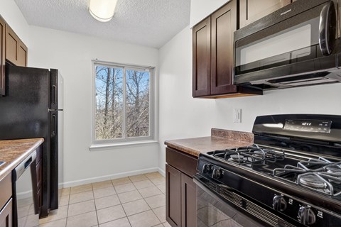 A kitchen with black appliances and brown cabinets.