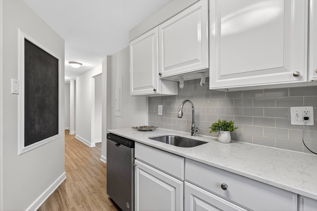 A kitchen with white cabinets and a blackboard on the wall.
