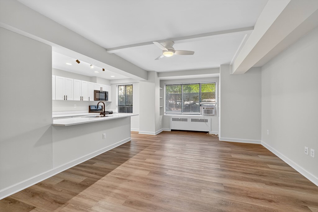 A spacious room with wooden flooring and a ceiling fan.