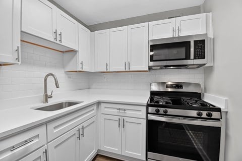 A kitchen with white cabinets and a black stove.