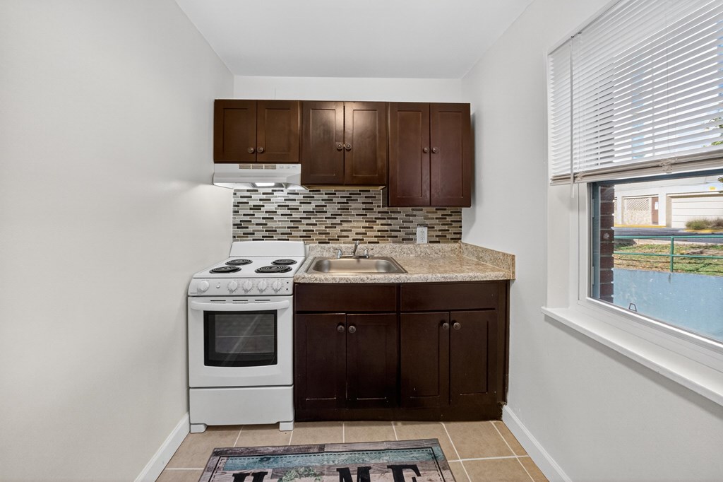 A kitchen with white appliances and brown cabinets.