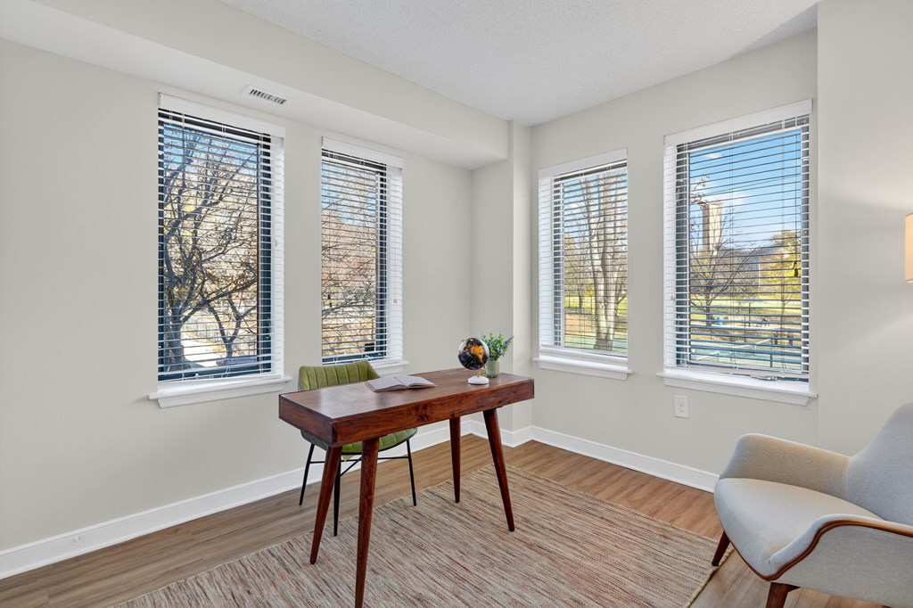 A room with a table, chairs and windows.