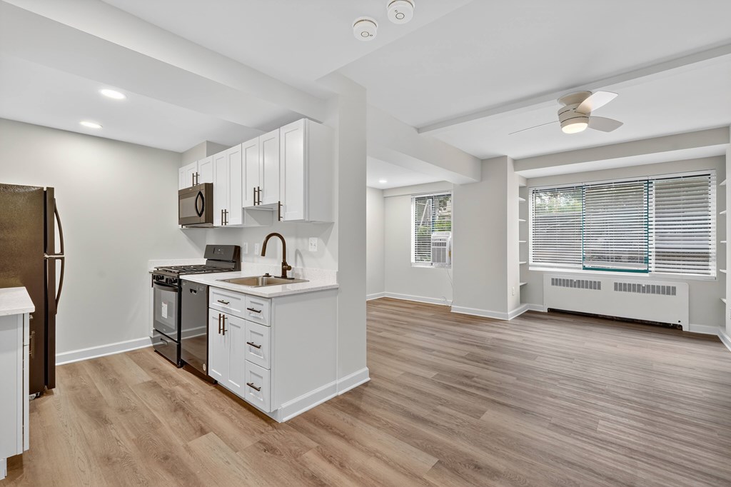 A kitchen with white cabinets and a wooden floor.