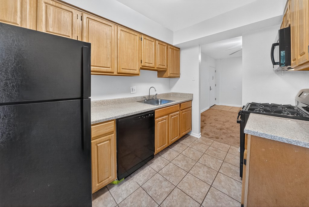 A kitchen with black appliances and wooden cabinets.