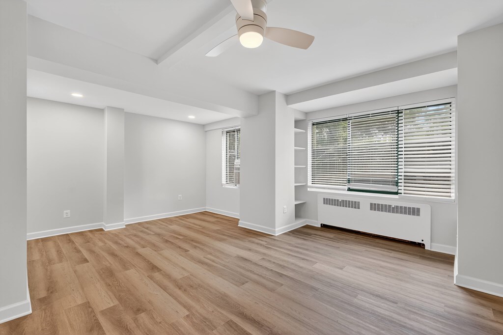 A room with a ceiling fan and a window with blinds.